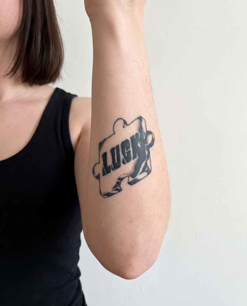 Luck Puzzle semi-permanent tattoo on forearm