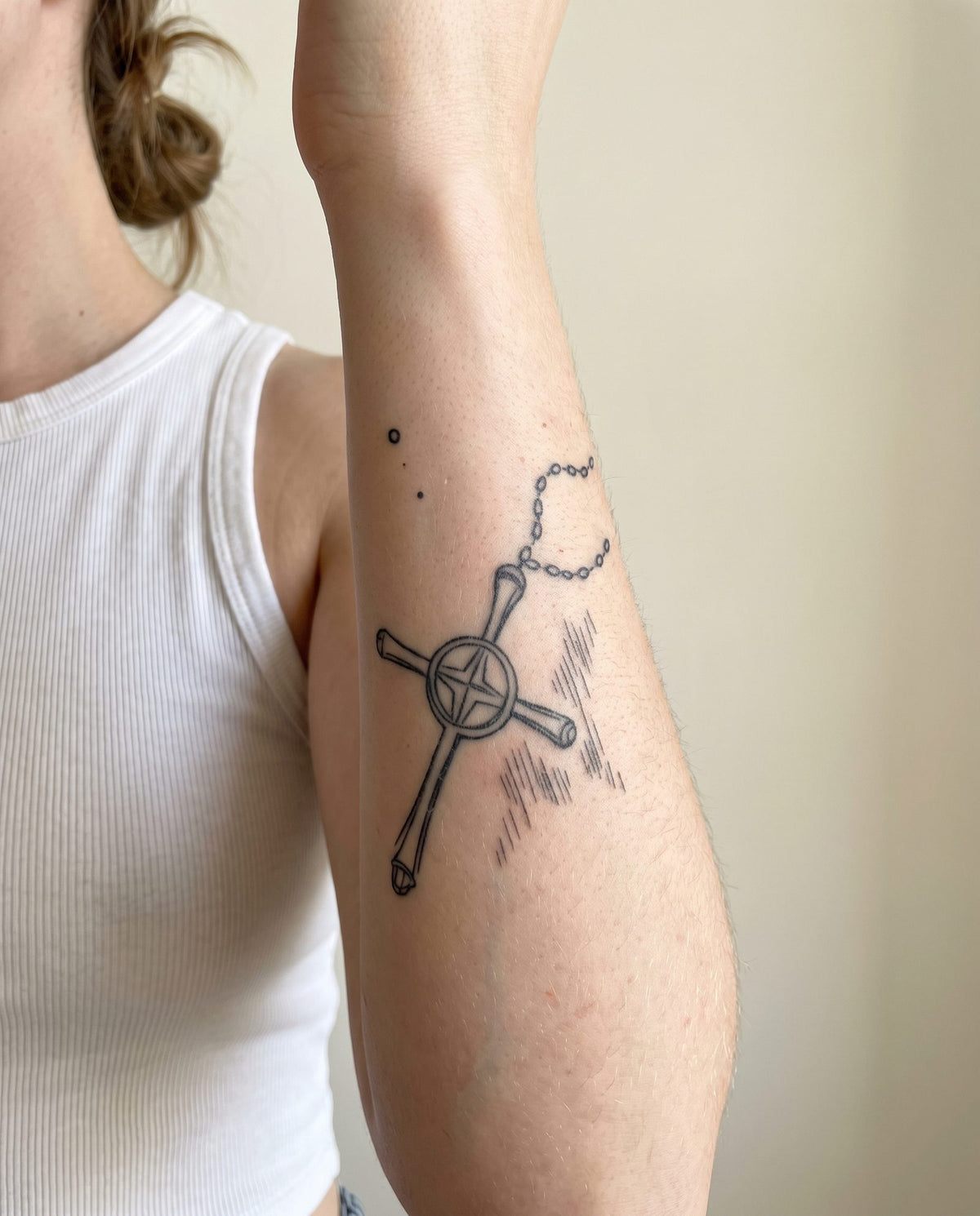 Quincy's Cross semi-permanent tattoo on inner forearm