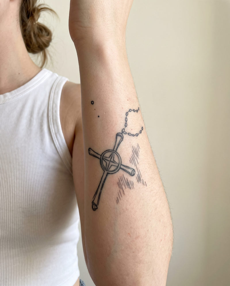 Quincy's Cross semi-permanent tattoo on inner forearm